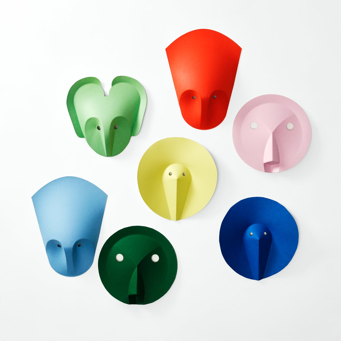 Assortment of colorful wall hooks in different shapes and sizes, mounted on a light background in green, red, pink, yellow, and blue tones.