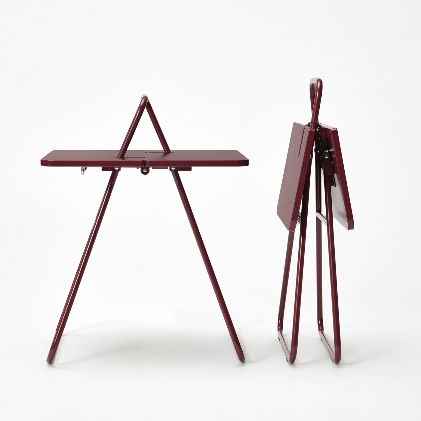 Two foldable steel tables in burgundy next to each other - one is folded and the other one is unfolded.