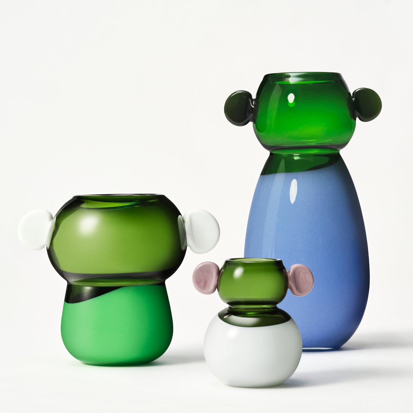 A collection of three green and coloured vases together, against a white backdrop.