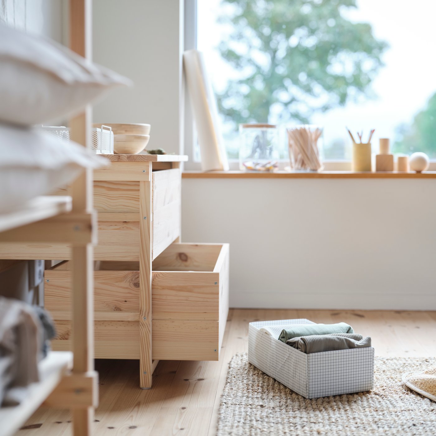 The KRONÖREN chest of drawers with an open drawer and a small storage box on the floor in front of it.