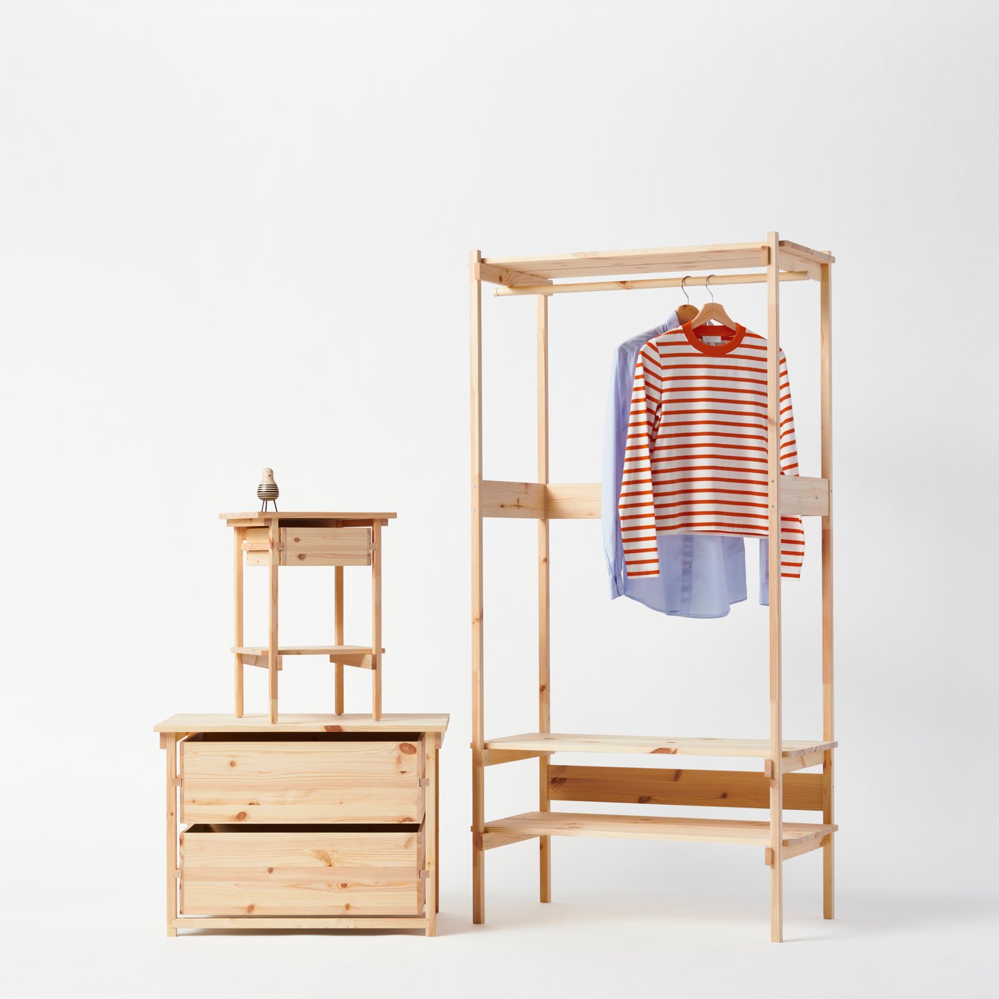 KRONÖREN bedside table on top of the chest of drawers, to the left of the open wardrobe that has a red stripe and blue shirt hanging from the clothes rail.