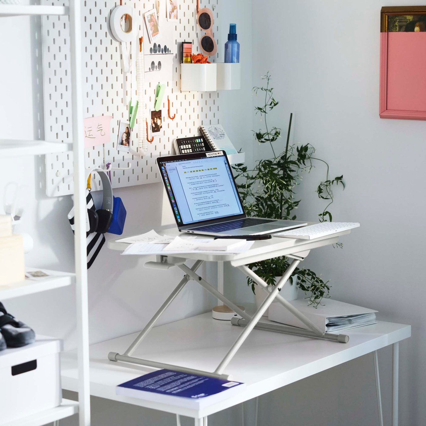 The corner of a white office desk with a laptop sitting on a stand.
