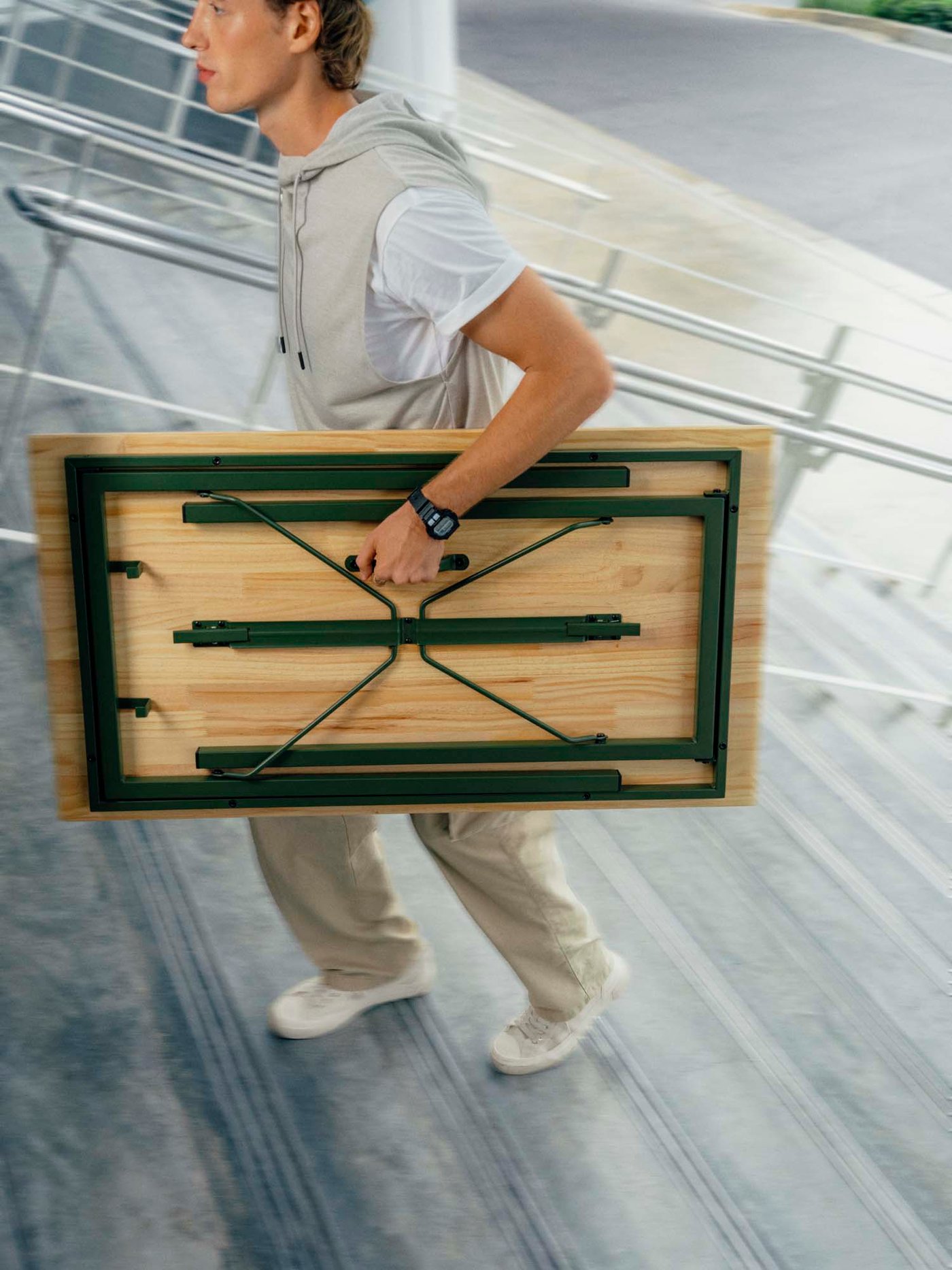 A person climbing stairs with a folded table.