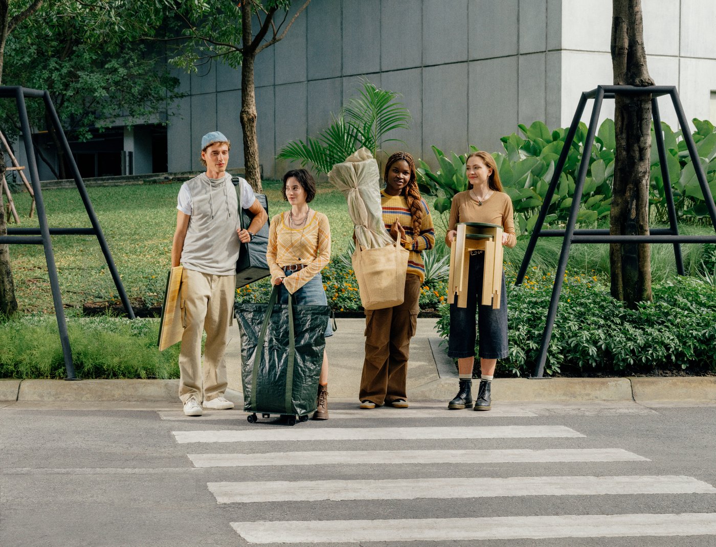 A group of people walking together outdoors carrying bags and home furnishing items.