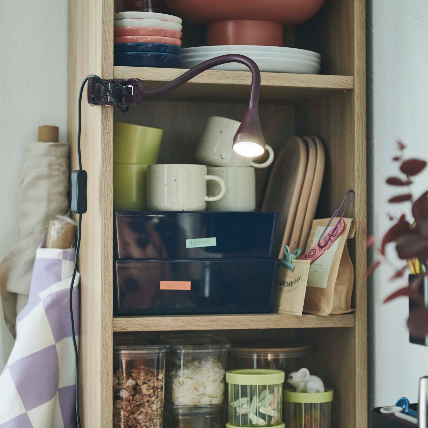Dinnerware, mugs and food storage containers on open light wood shelving.