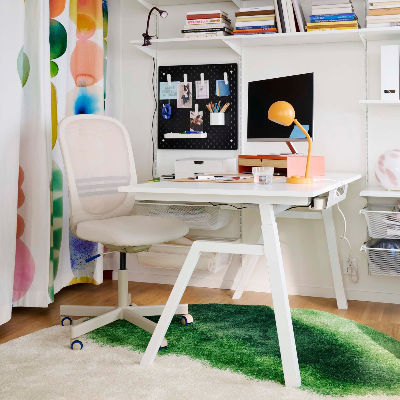 A colourful home office space with a white height adjustable desk with a cosy rug below.