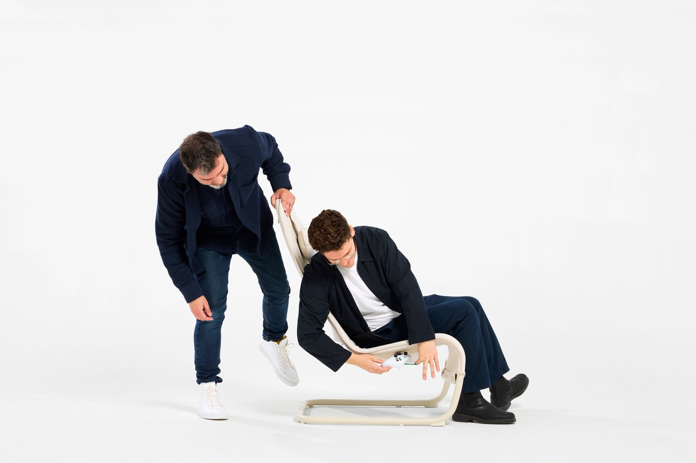 Two designers testing a YXSTABY gaming chair with integrated headrest and controller storage.