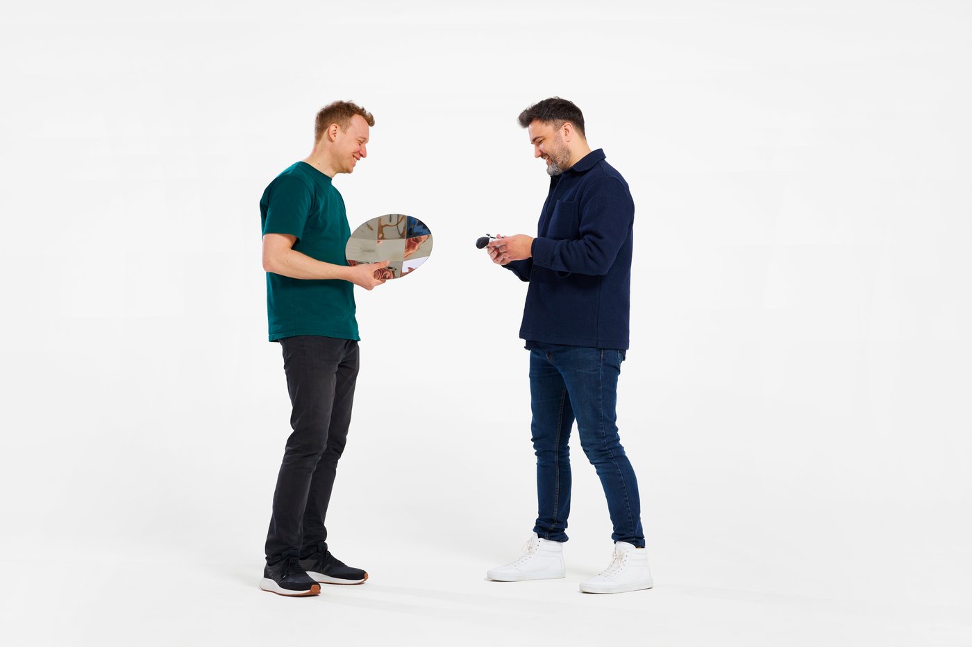 Two designers holding and discussing a stainless steel platter inspired by an Xbox controller D-pad.