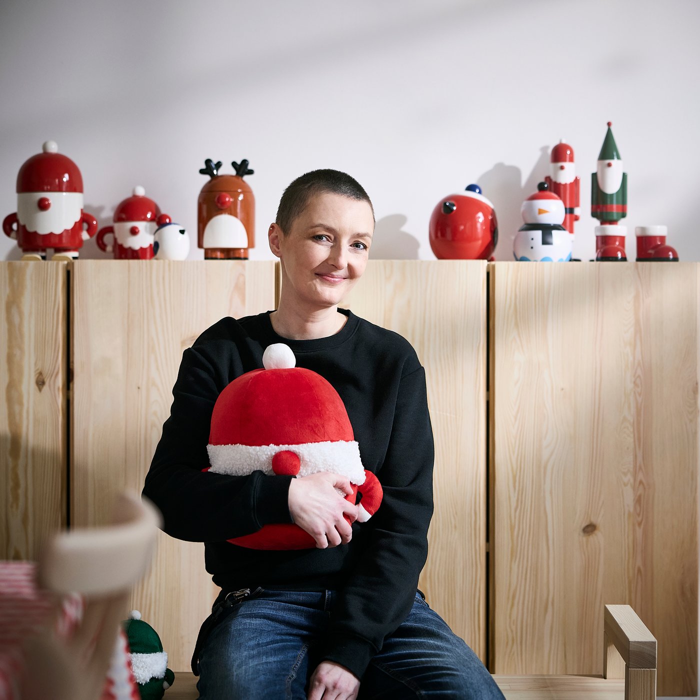 IKEA designer Marta Krupińska holding a large red Santa-shaped soft toy.