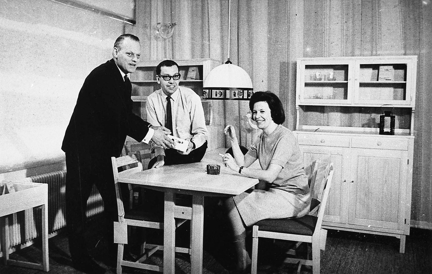Erik Wørts stands, while Gillis Lundgren and Karin Mobring sit at a table. They are smiling.