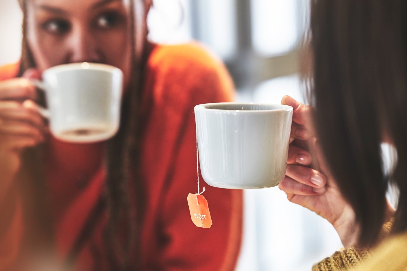 Two people drinking cups of tea in white mugs.