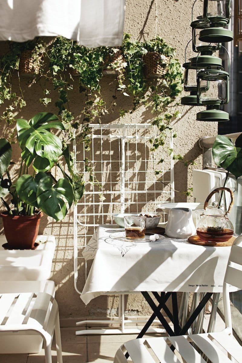 A sunny balcony with a small table and a folded drying rack hanging on the wall.