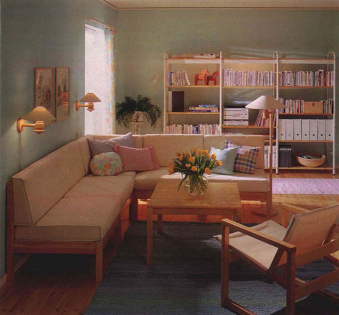 A photo of a living room with a corner sofa unit, bookshelves in the background and a RYD armchair, from the 1990 IKEA Catalogue.