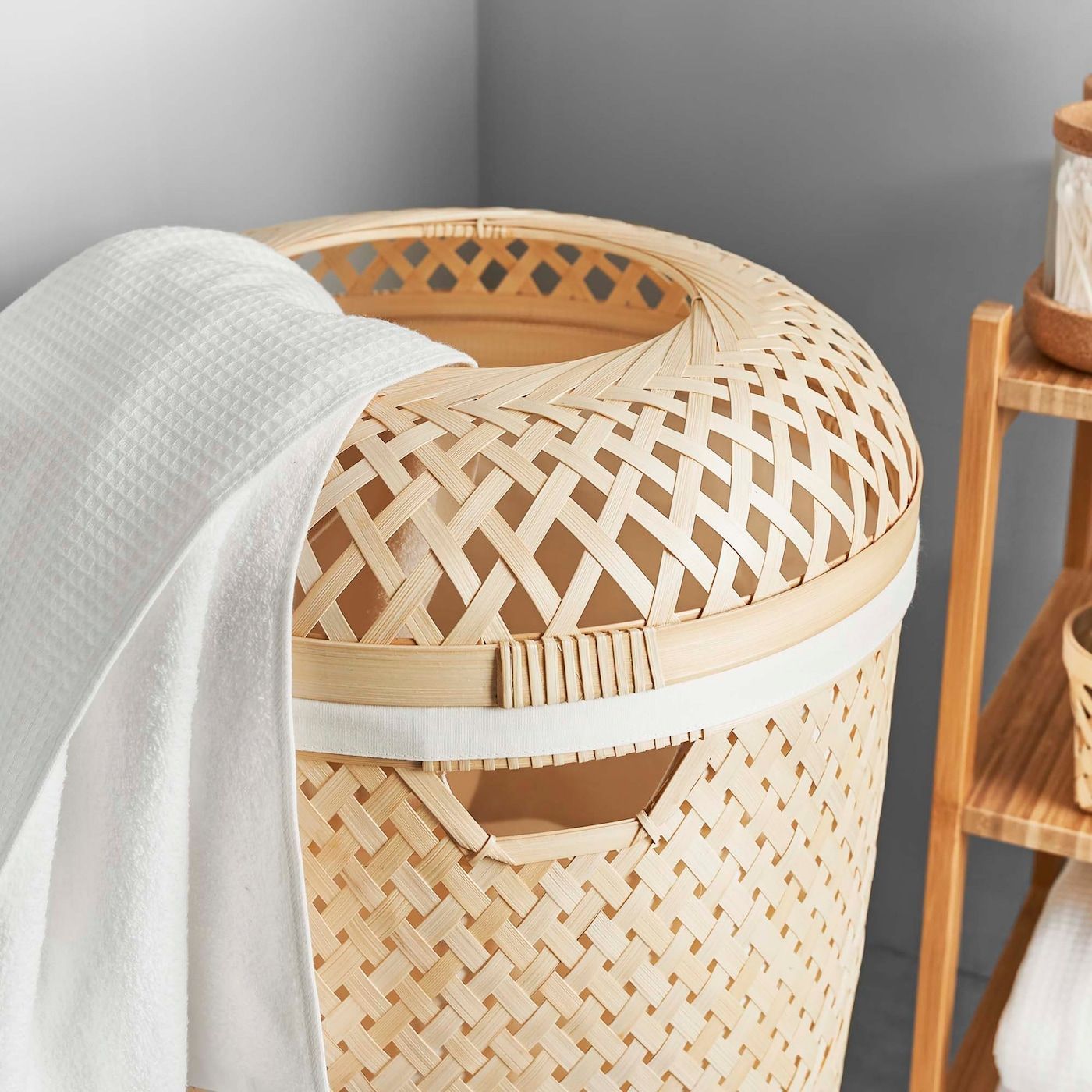A SALUDING laundry basket  in the corner, with shelves next to it.
