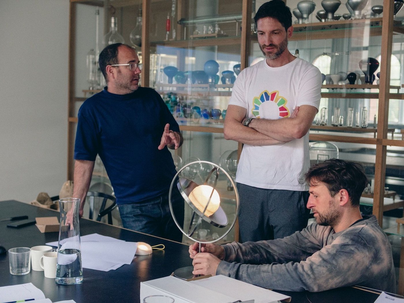 IKEA and Little Sun design team gather around a table to look at a SAMMANLÄNKAD table lamp.