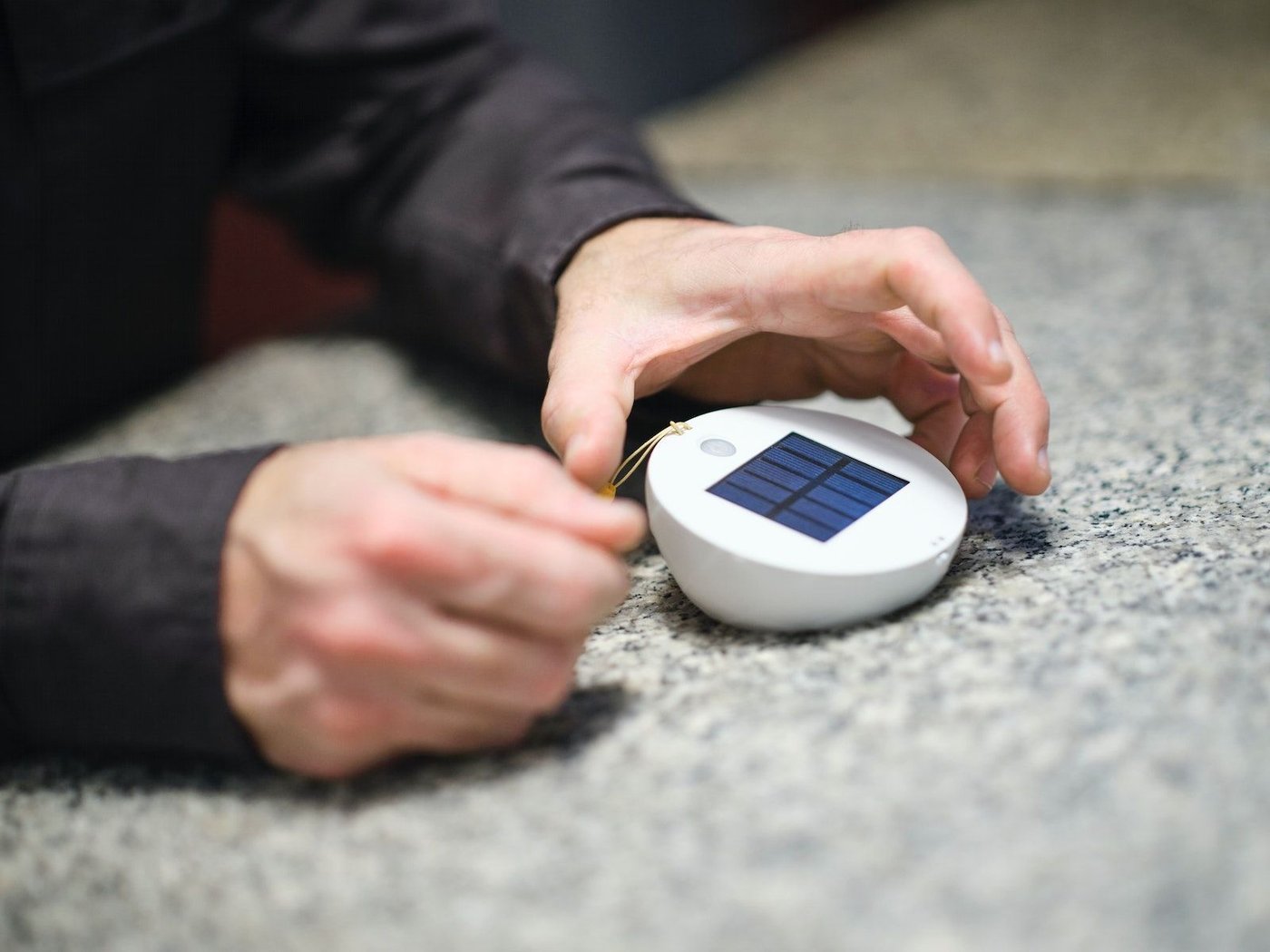 Hands holding the SAMMANLÄNKAD LED solar-powered lighting upside down to reveal its solar panels.