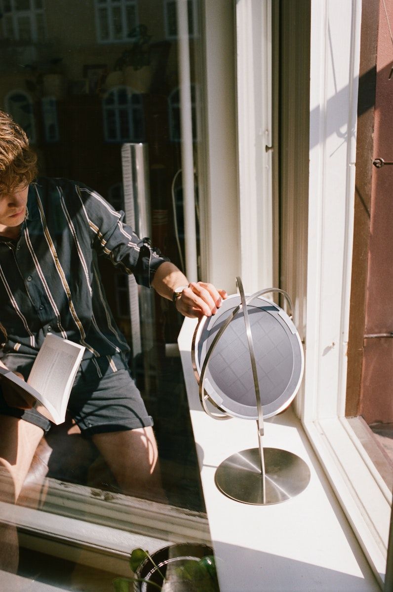 A person placing a SAMMANLÄNKAD table lamp on a sunny windowsill.