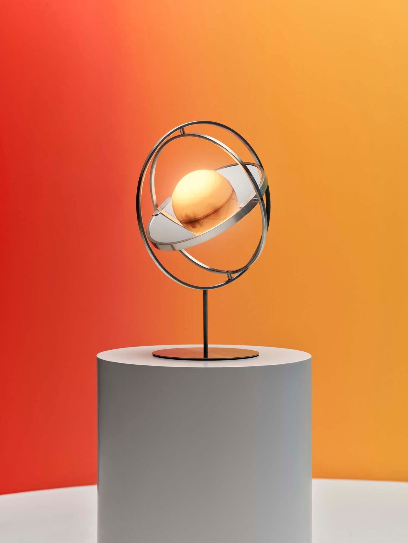 A solar powered stainless lamp with a mirror standing on a podium in a room with yellow and red walls.