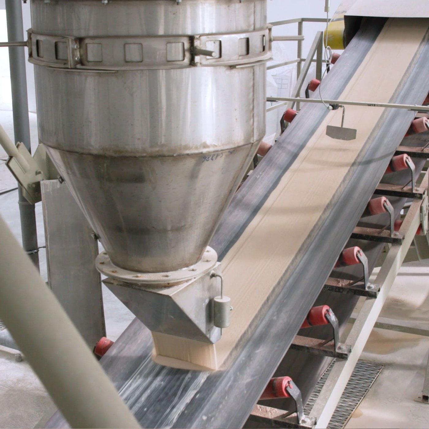 Ceramic slip being sprayed onto a conveyor belt in a large industrial facility.