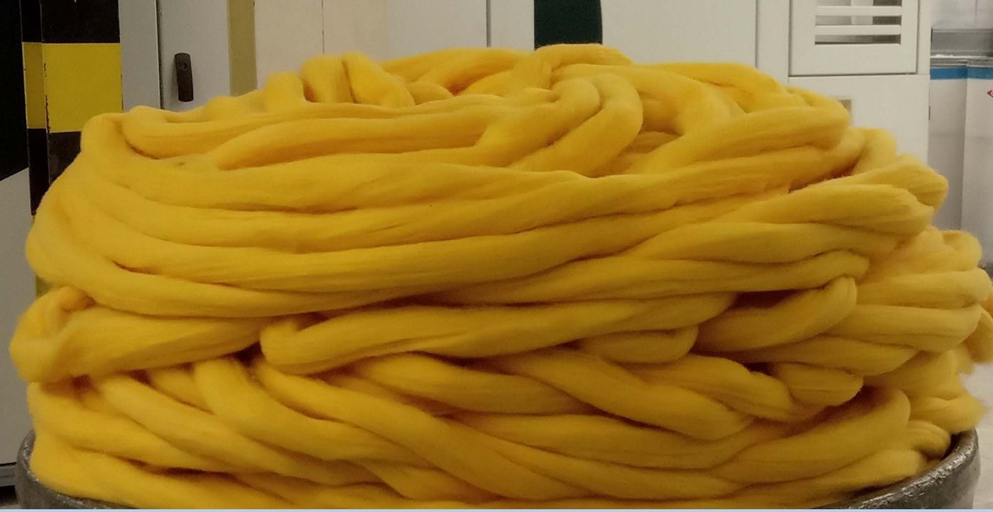 Pile of thick yellow yarn in an industrial setting.