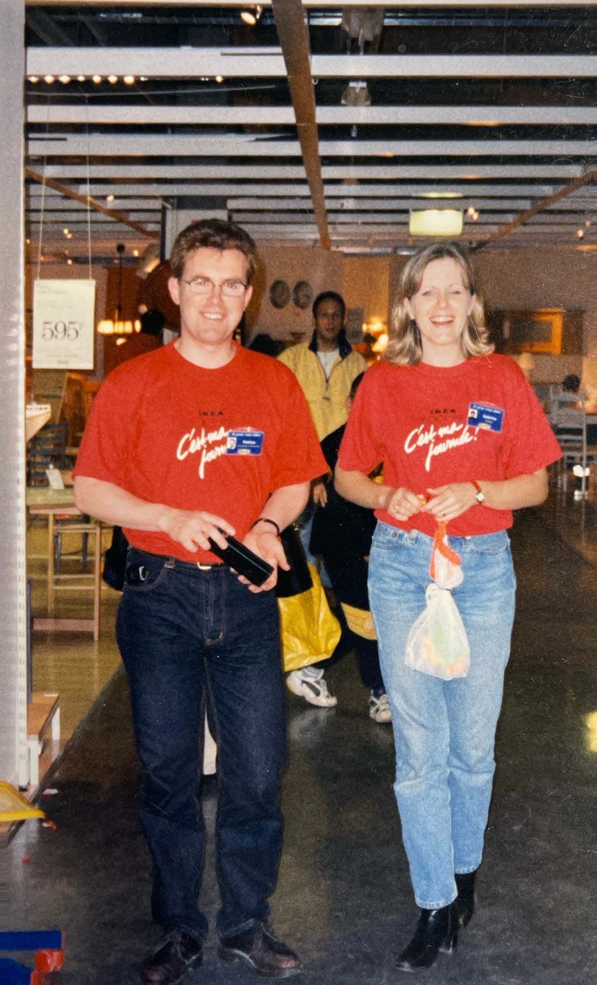An image of Sabrina with another co-worker walking through the storre. They wear matching red t-shirts.