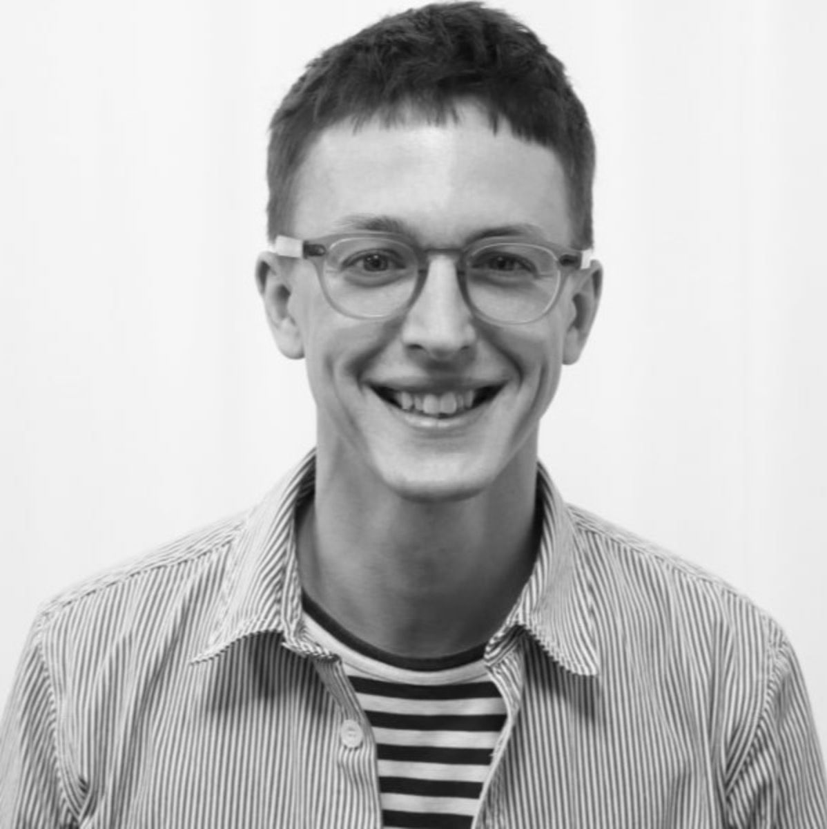A black and white, head and shoulders photograph of a smiling person.