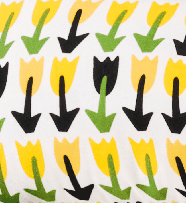 A close-up of a yellow, green, black and white tulip print pillow.