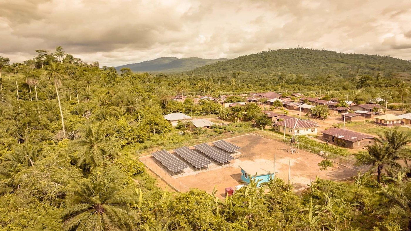An aerial view of solar panels powering nearby buildings in a forest clearing.