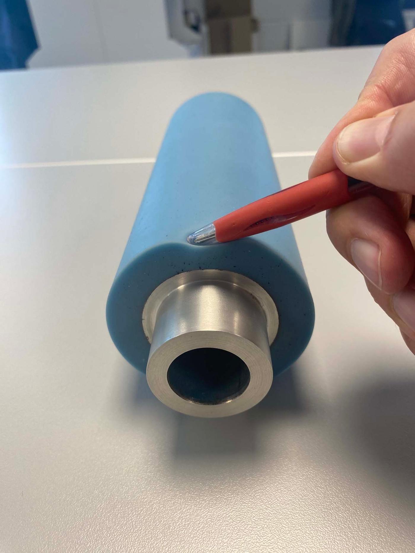 A hand pushes a pen into the foam of a soft roller, demonstrating its softness.