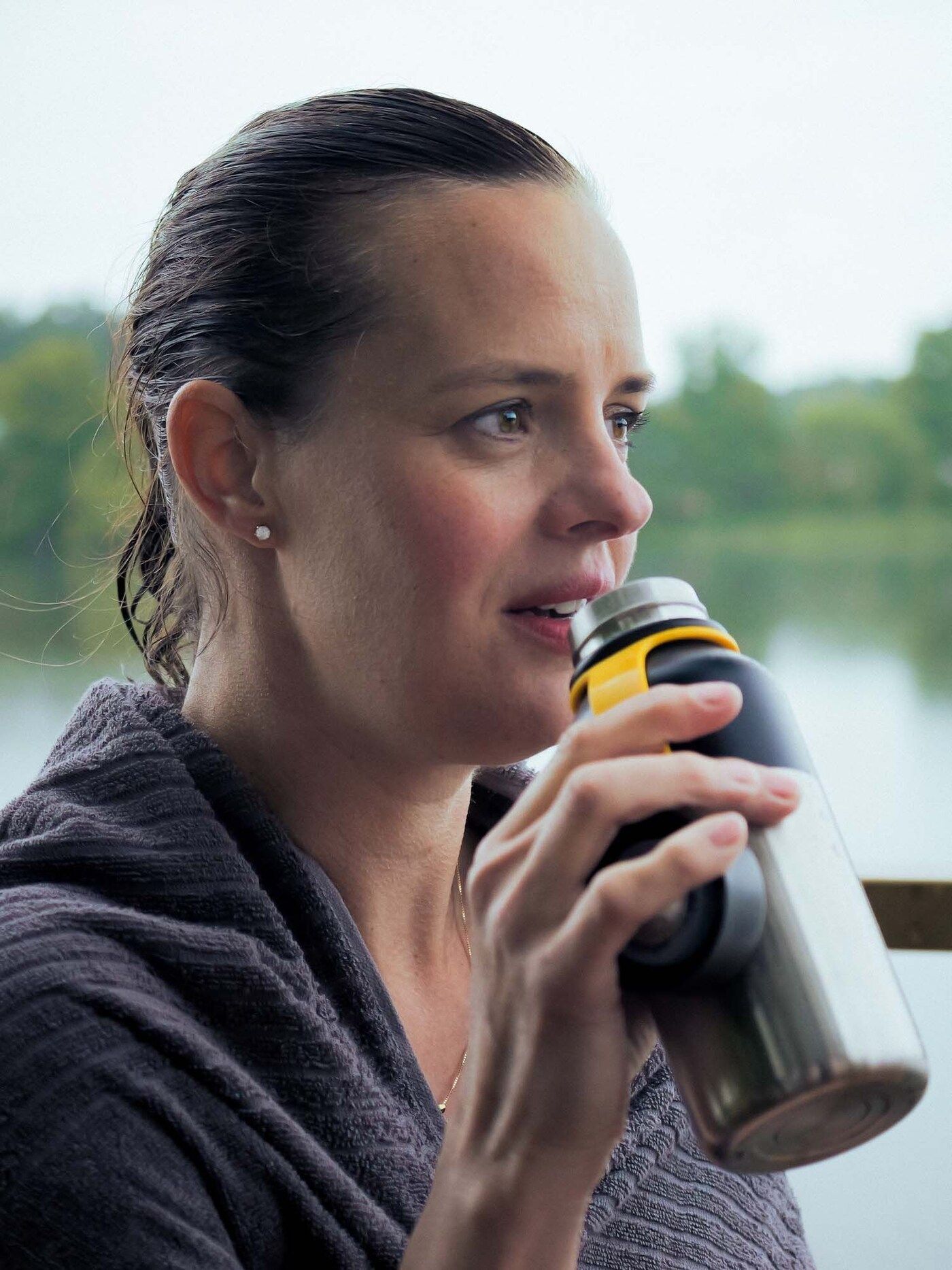 Paulina drinks warm tea from a flask after swimming in the lake
