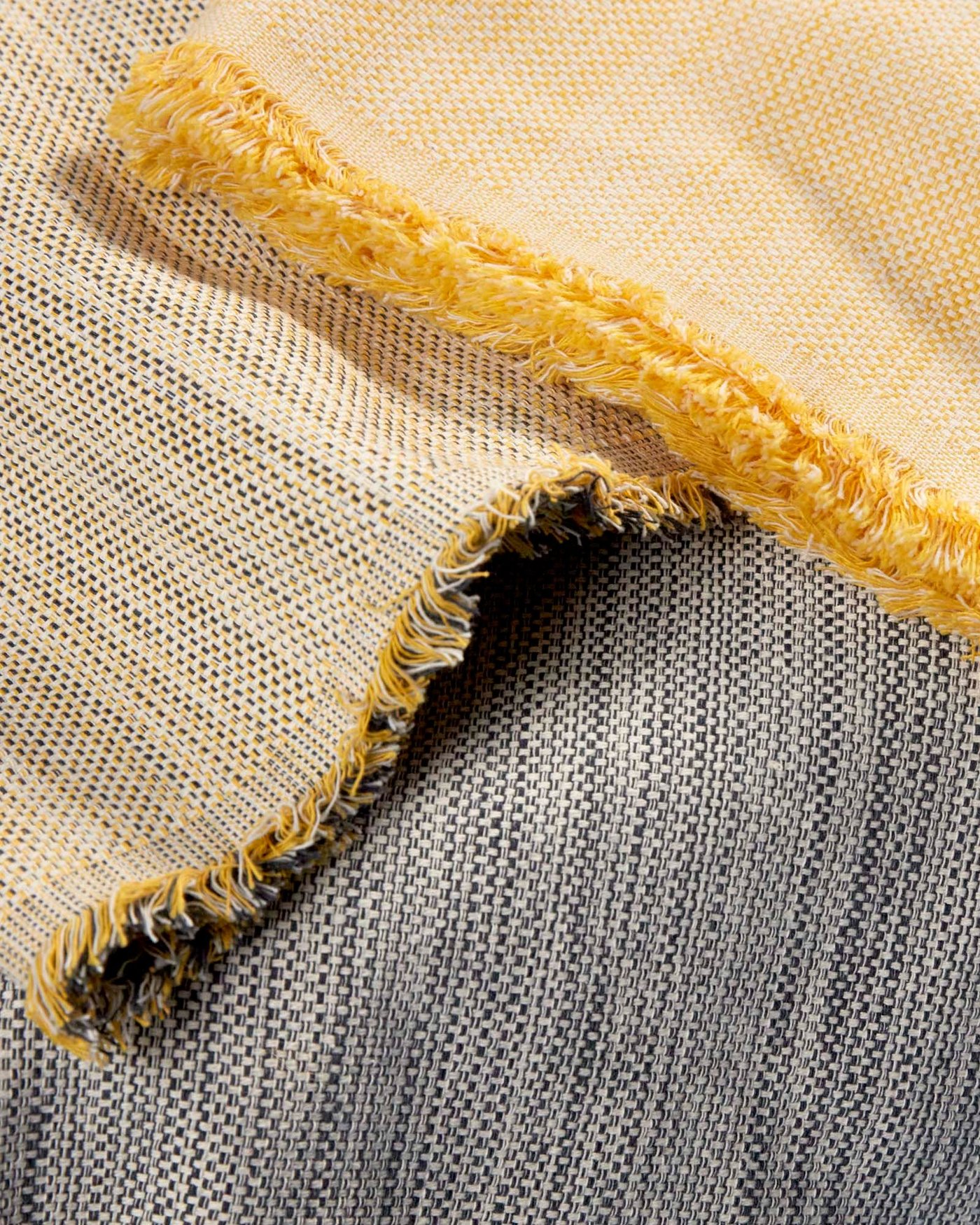 Close up of VÄXELBRUK throws in three different colours: yellow, blue and a yellow-blue blend.