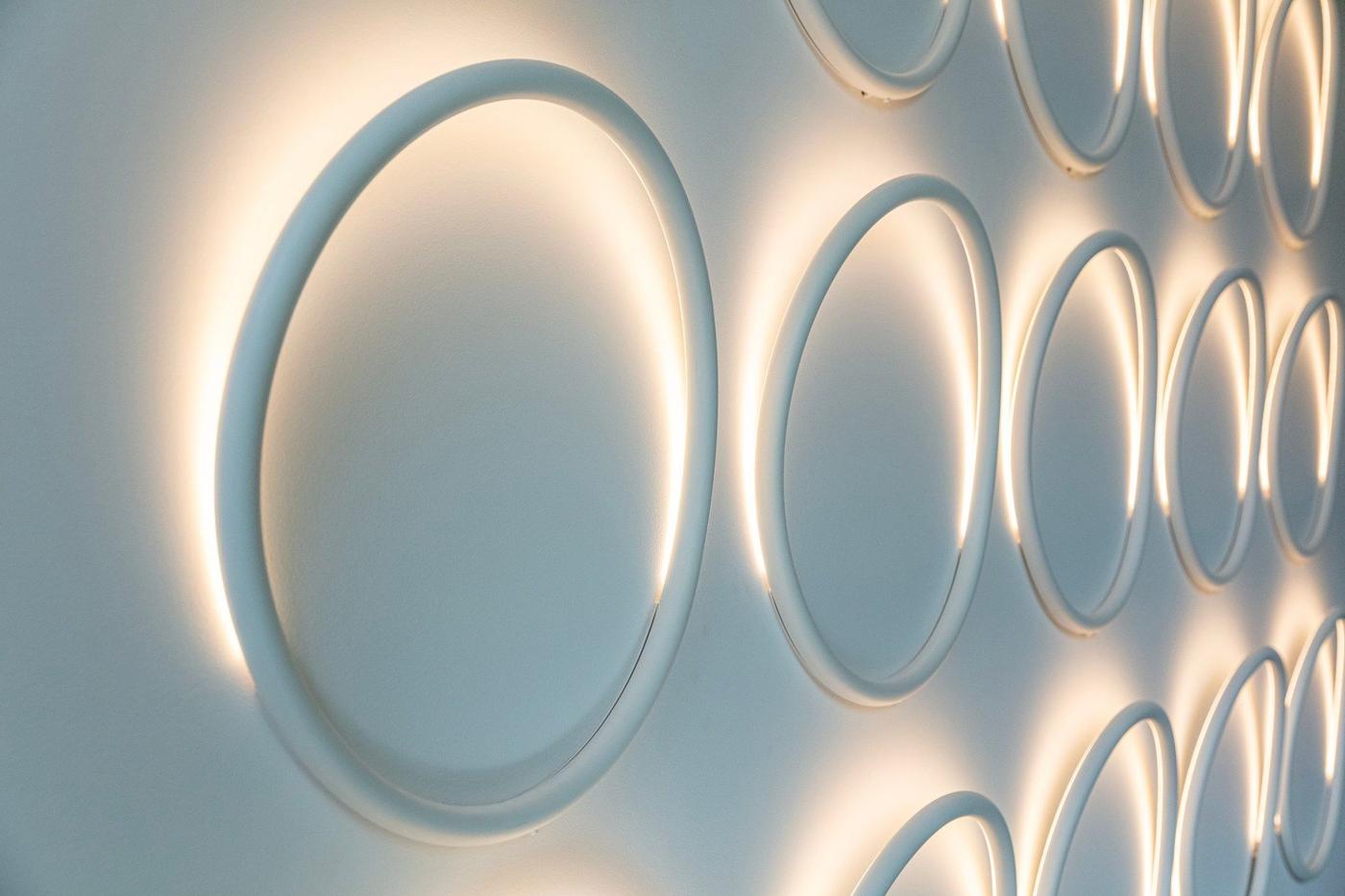 A wall illuminated with circular ring lights from the VARMBLIXT collection.