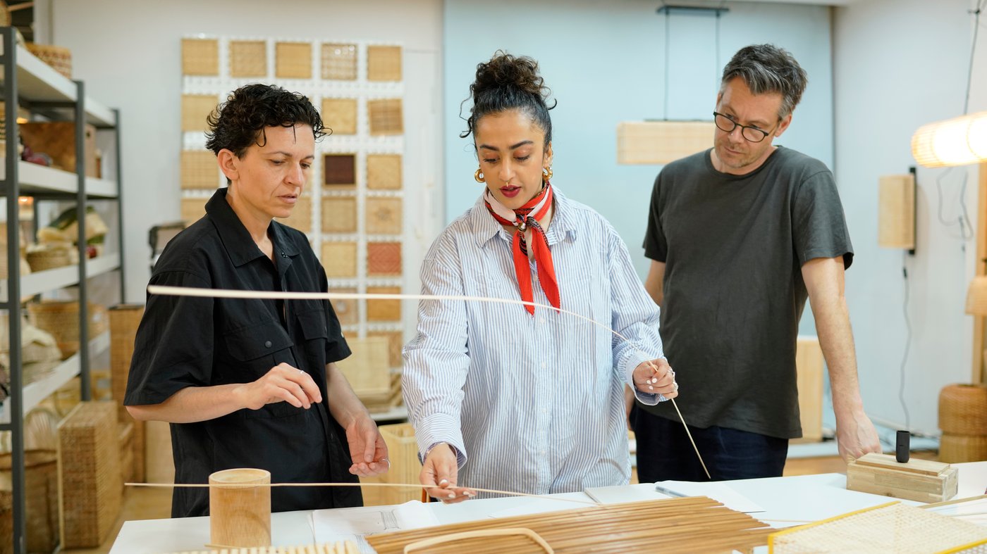 Chiara Ripalti, Akanksha Deo and Andreas Fredriksson looking at woven bamboo samples in a studio.