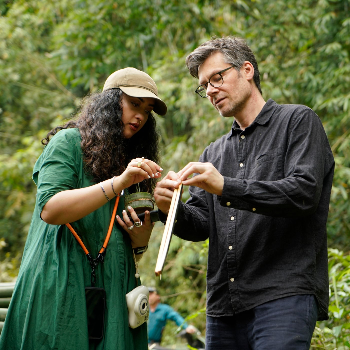 Akanksha Deo and Andreas Fredriksson outdoors examining pieces of bamboo plant.