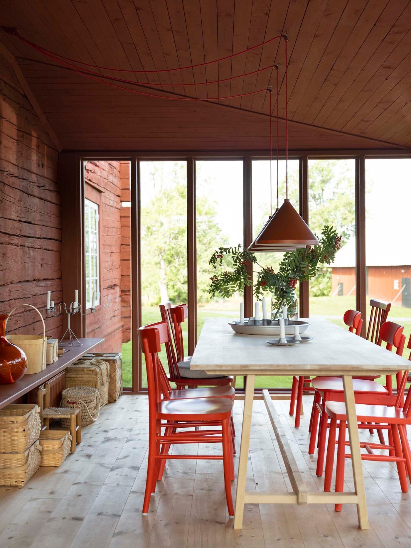 A dining area with red walls, ceiling, pendant lamps and chairs.