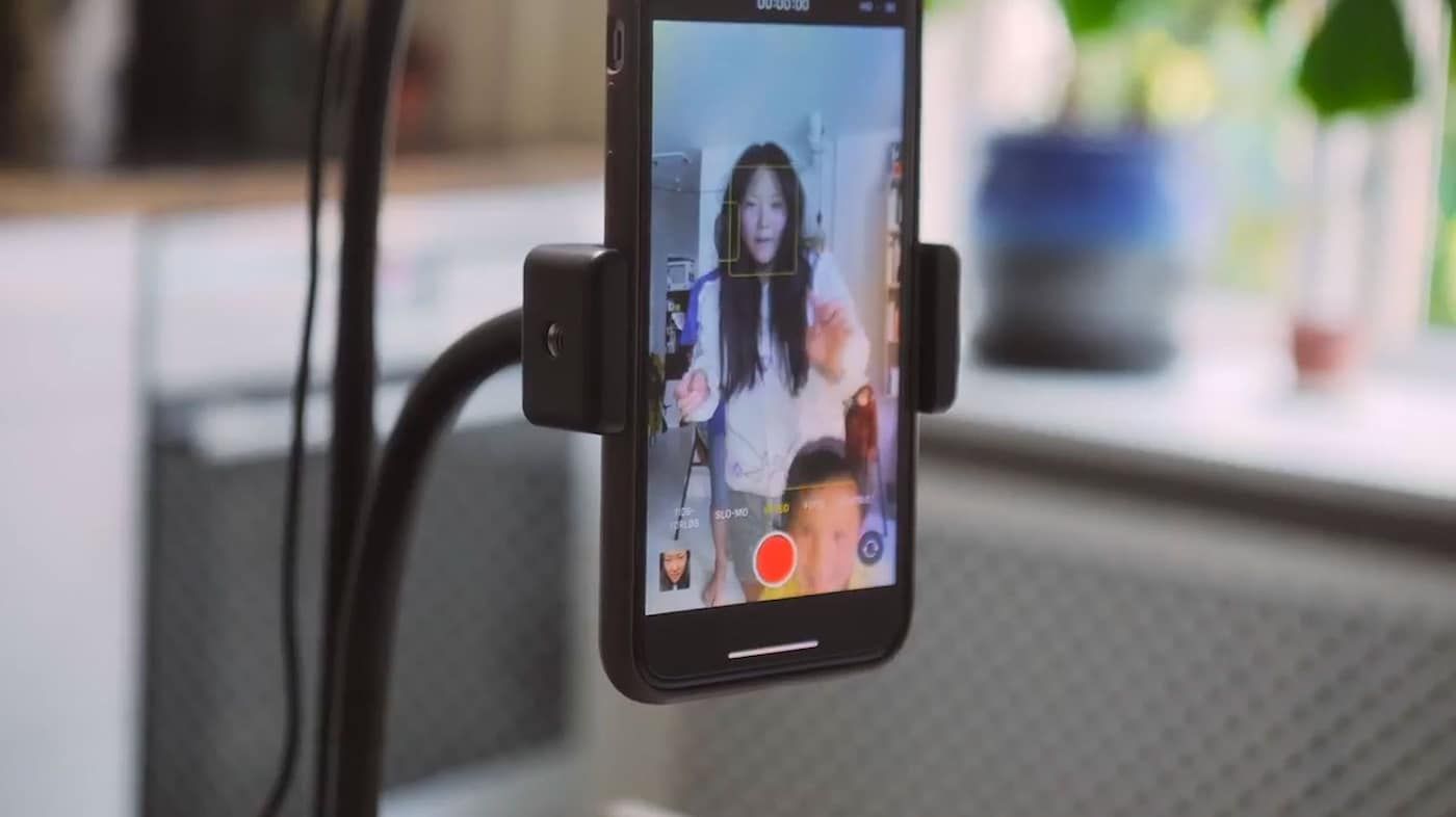 A still image from a video showing a smartphone attached to a holder. The phone is filming Rosa and her son dancing.