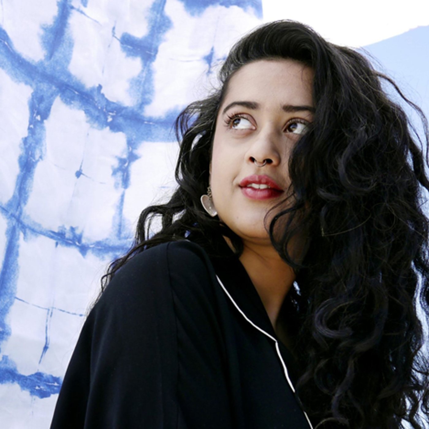 Akanksha Deo, designer at IKEA of Sweden, set against a blue and white textile backdrop. She looks away from the camera.