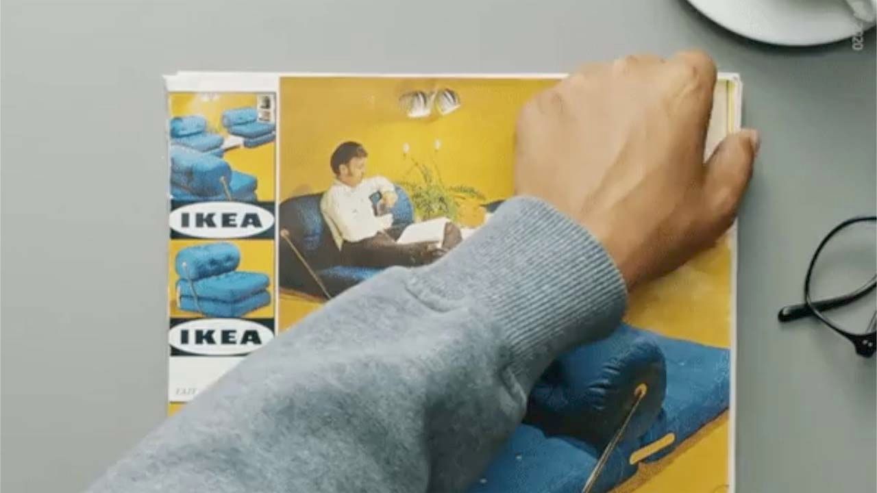 A hand and arm across the cover of a vintage IKEA catalogue, poised at the moment just before opening the publication.