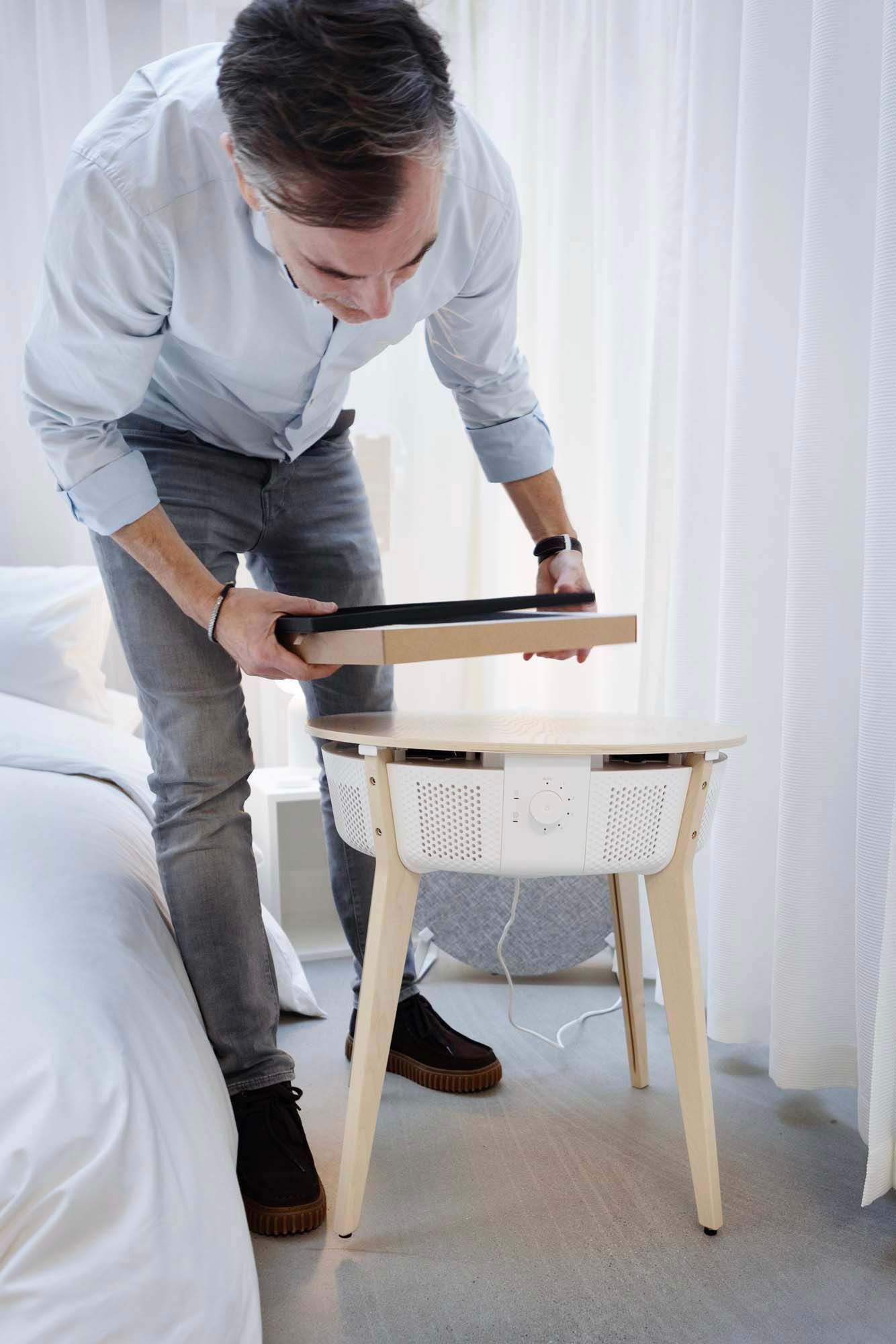 IKEA product design developer Stjepan Begic examines a STARKVIND table with air purifier in a white environment.