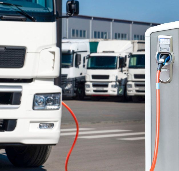 An electric charging station in front of a white heavy truck.