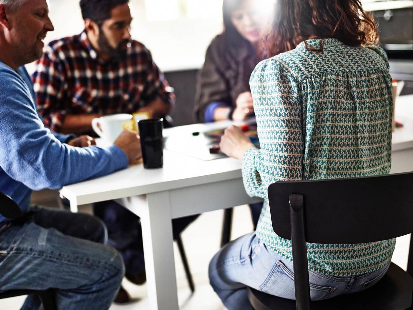 A group of people seated around a white table.