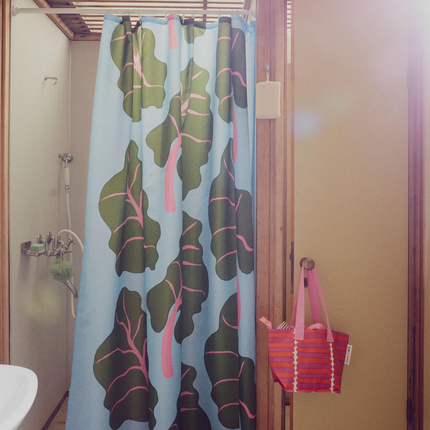 A bathroom with a light blue shower curtain with a rhubarb pattern.