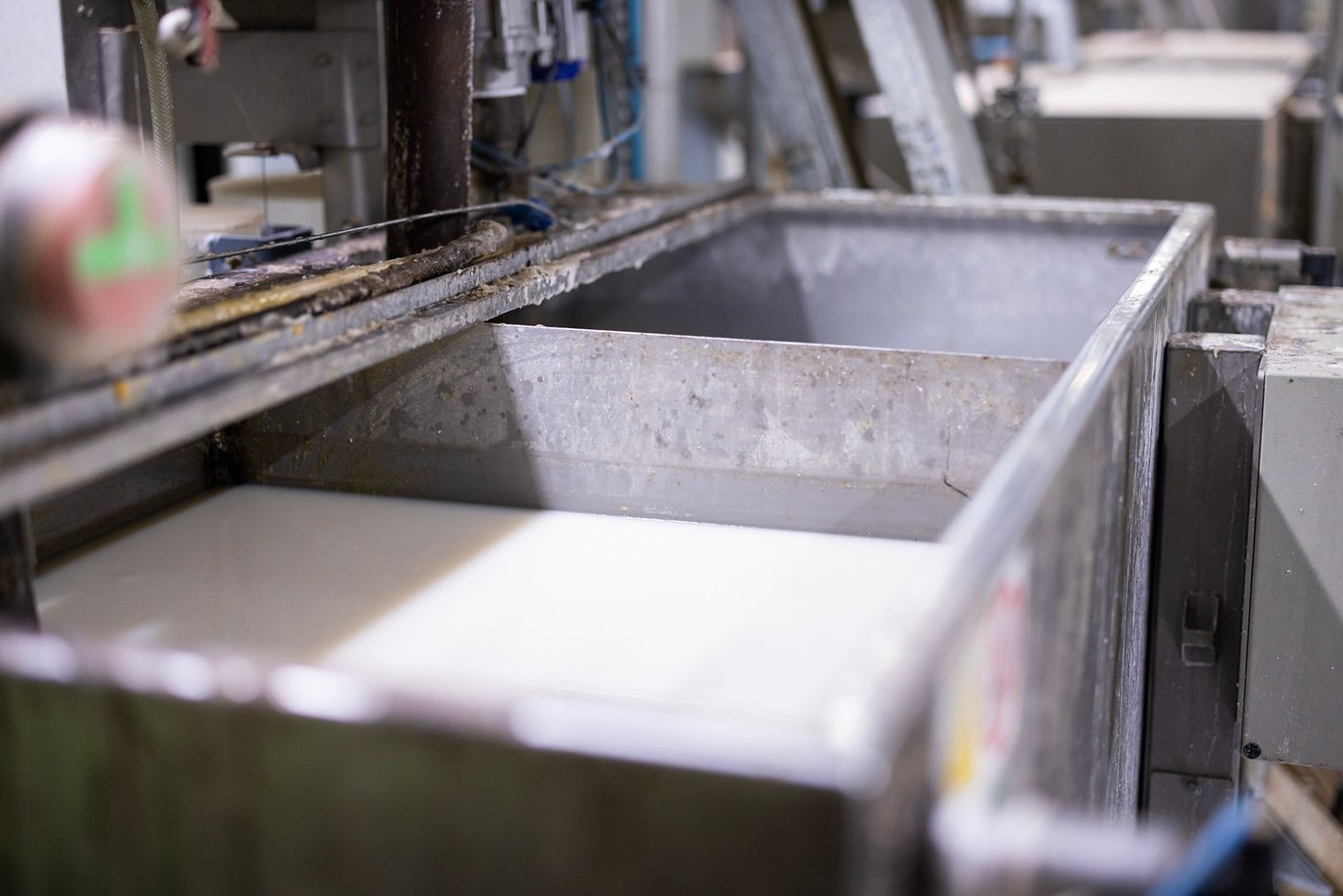 A metal container filled with glue standing in an industrial production environment.