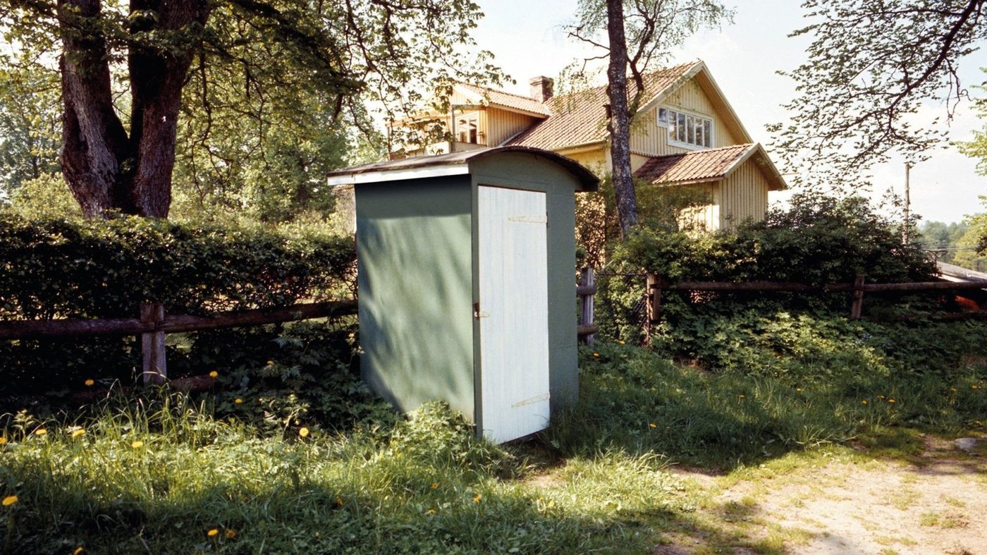 A small green shed next to a yellow house.
