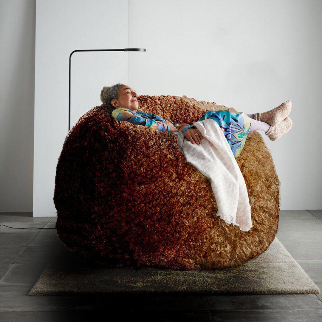 A person sitting in a giant fluffy meatball beanbag.