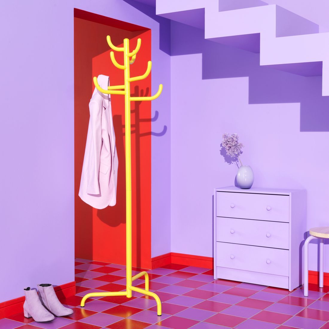 A yellow coat hanger standing in a room with purple walls. 