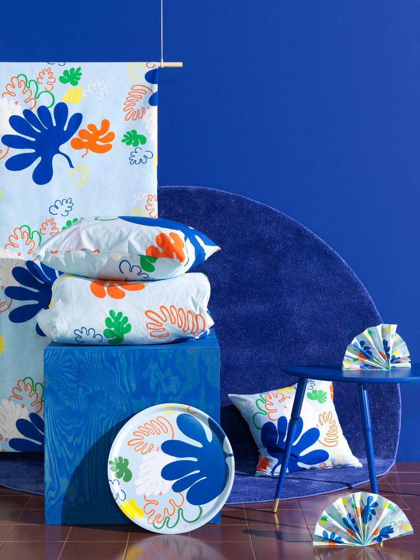 Two pillows and a tray with a leaf pattern on a blue stand.