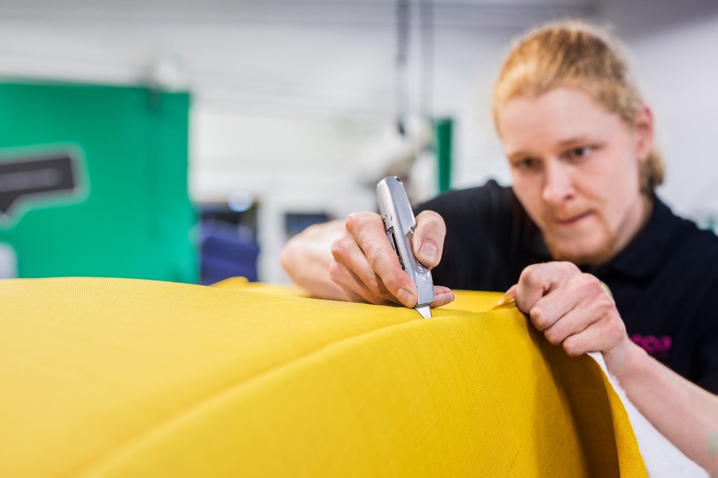 An IKEA co-worker reupholstering an armchair with bright yellow fabric.