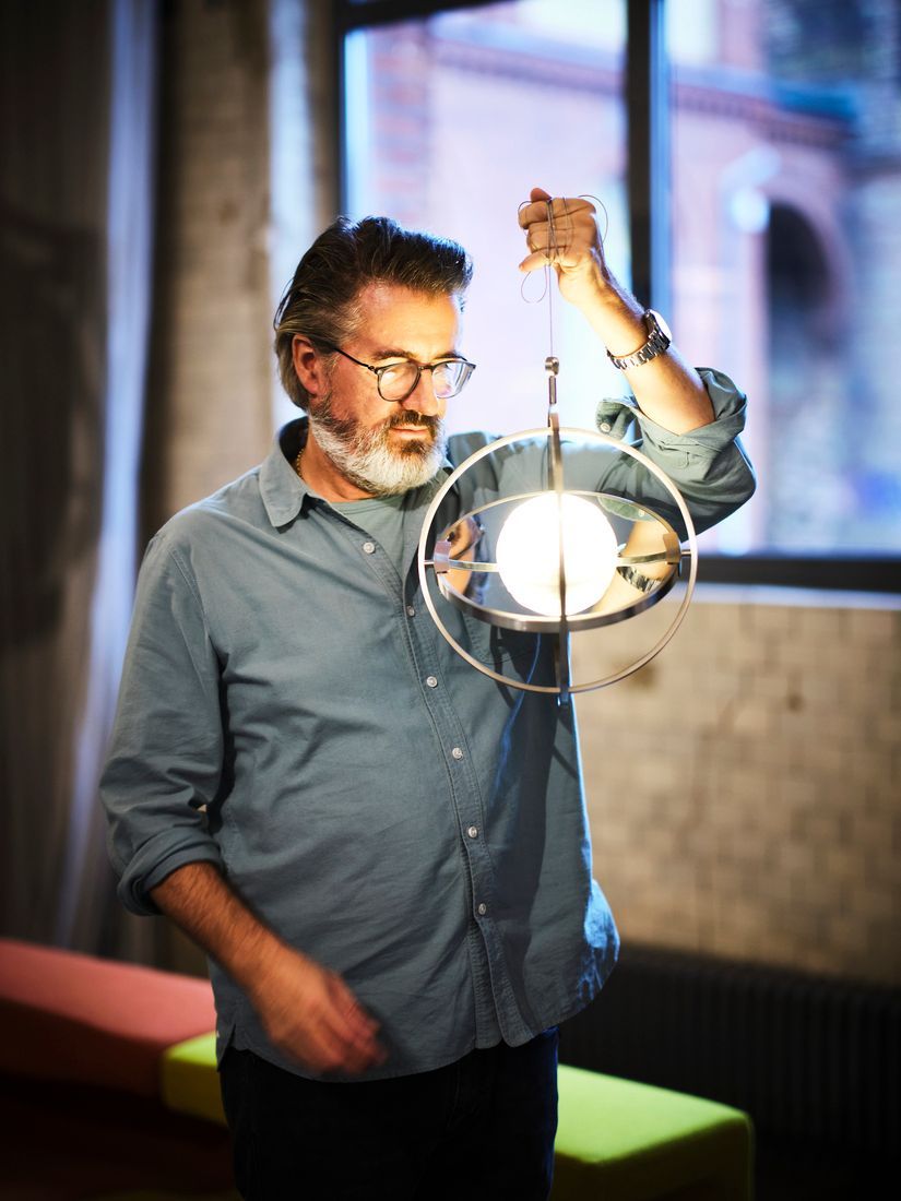 A man with a beard and glasses holding a stainless lamp with a mirror.