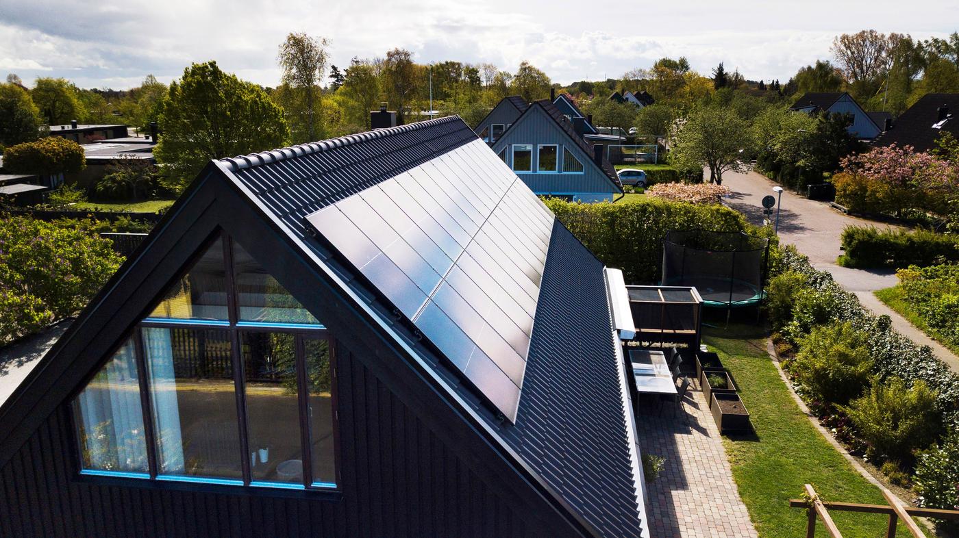 Solar panels on the roof of a black suburban house.